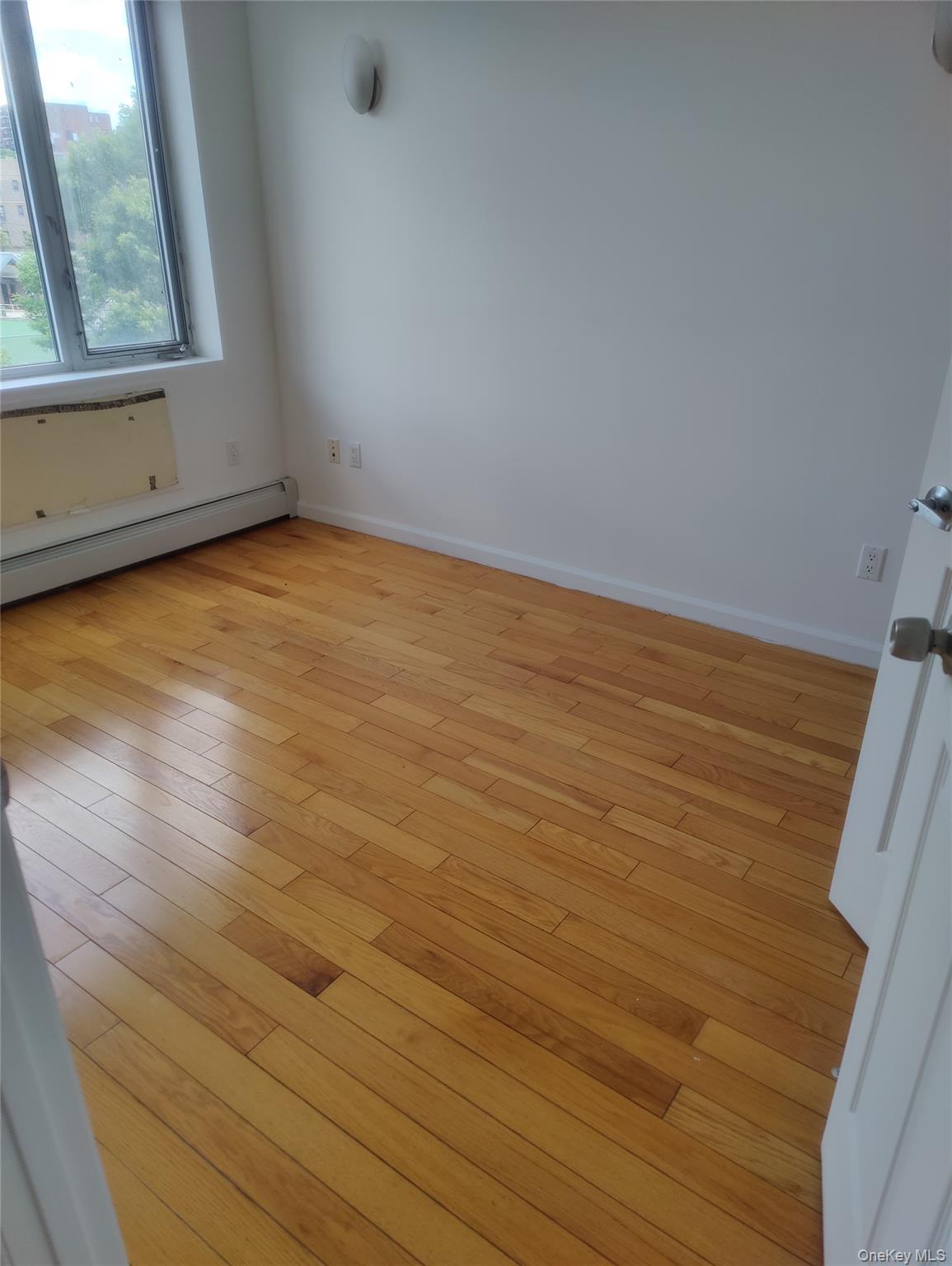 136-21 Latimer Place, Unit 3K Queens, NY 11354 - Photo 5 of 7 a view of an empty room with wooden floor and a window
