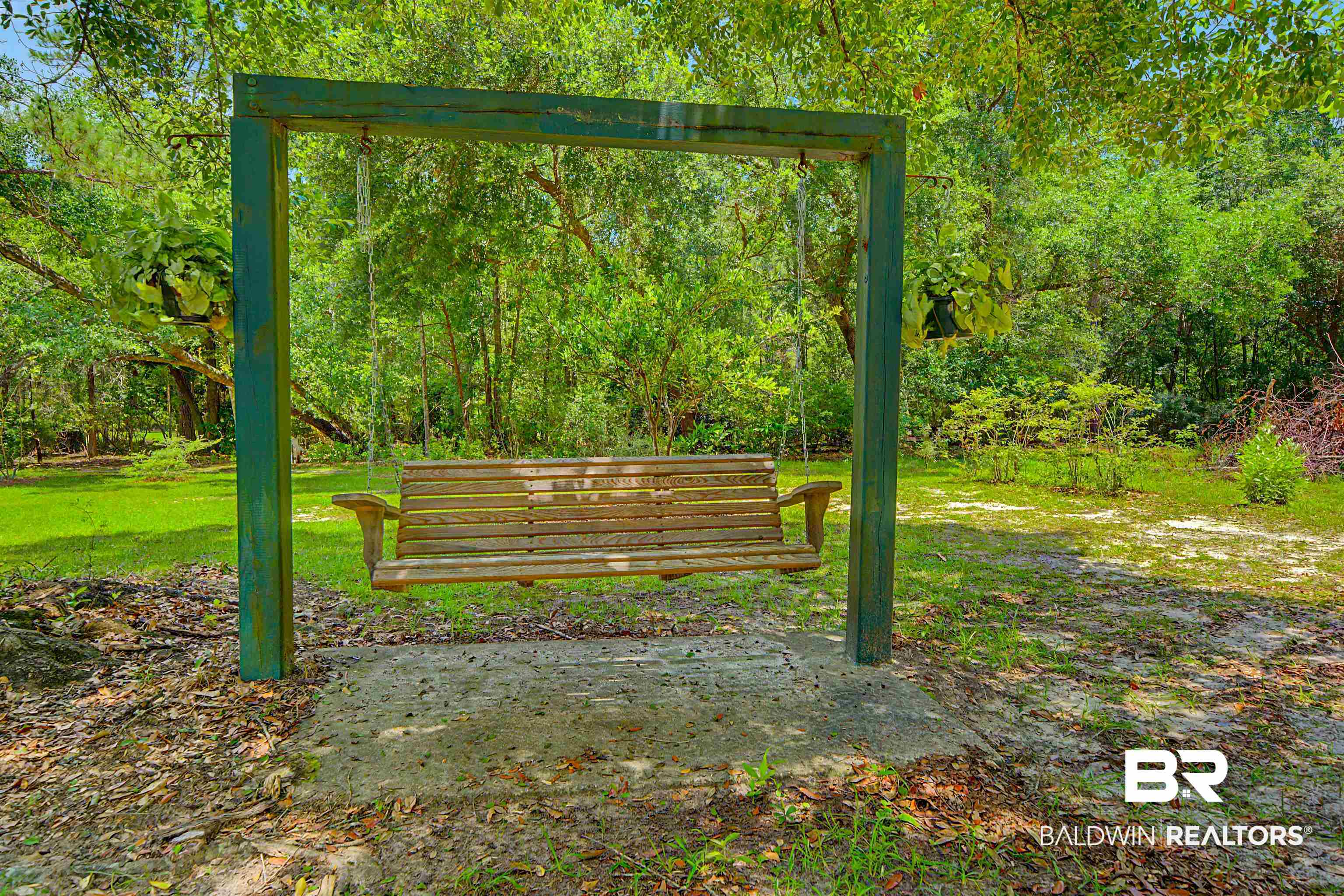 22963 Highway 98 Foley, AL 36535 - Photo 36 of 52 Wood-slat porch swing with armrests, suspended from a dark green frame, set on a concrete pad