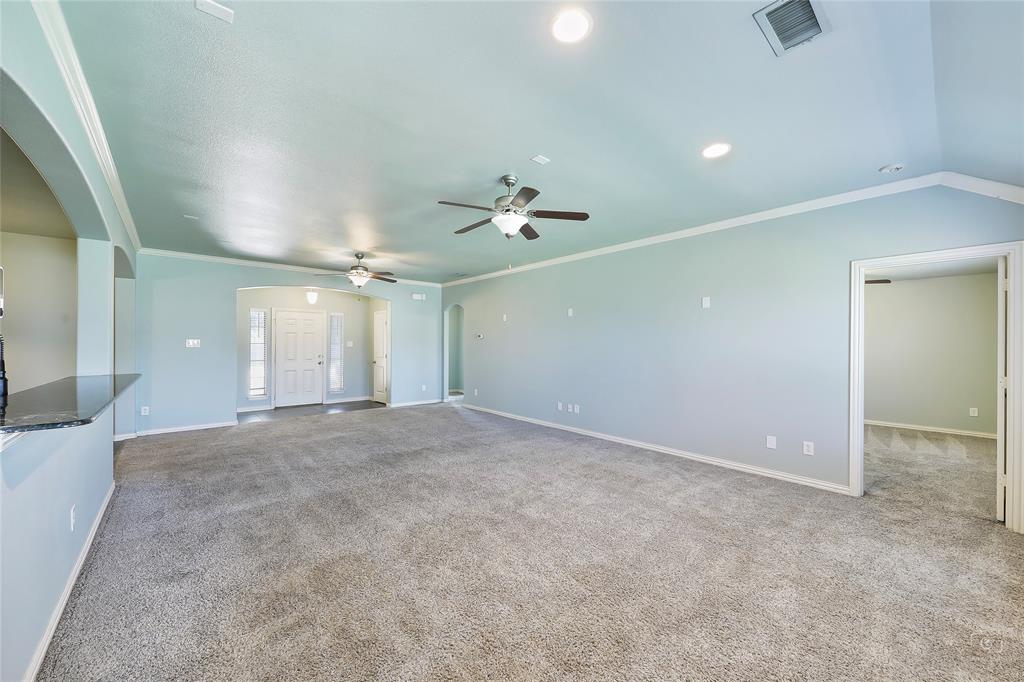 6601 Pine Hills Lane Denton, TX 76210 - Photo 11 of 23 Unfurnished living room with arched walkways, crown molding, light carpet, and a ceiling fan