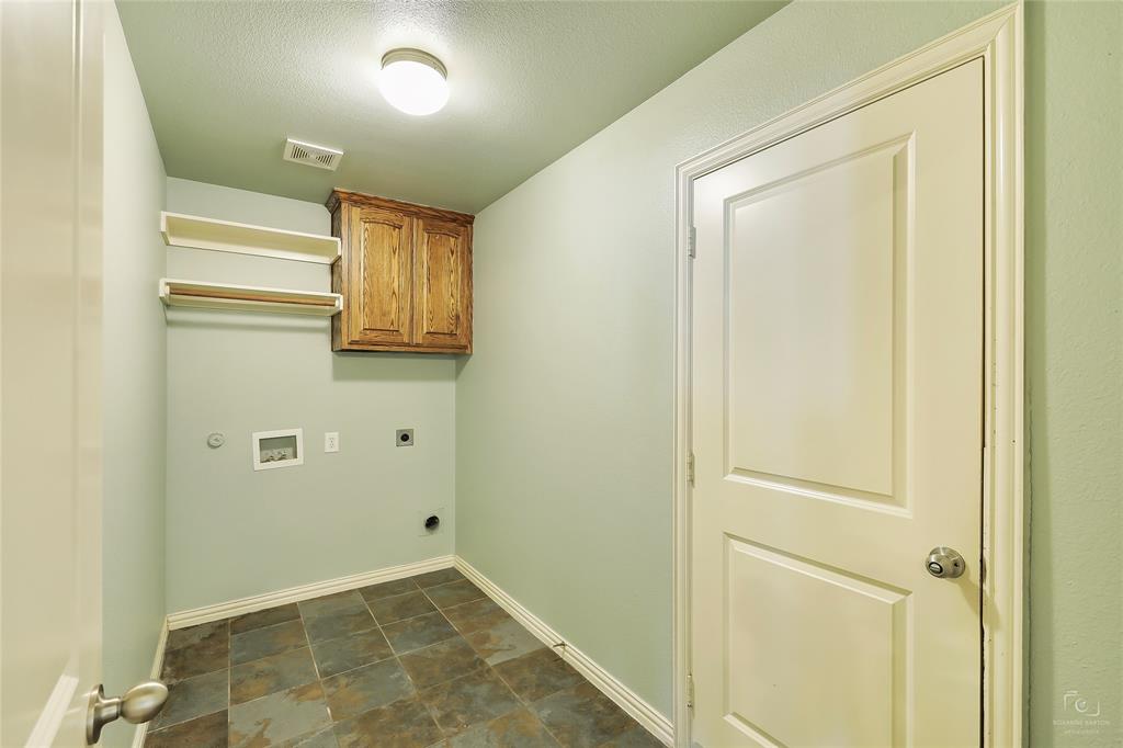 6601 Pine Hills Lane Denton, TX 76210 - Photo 21 of 23 Laundry room with electric dryer hookup, washer hookup, stone finish floors, cabinet space, and a textured ceiling