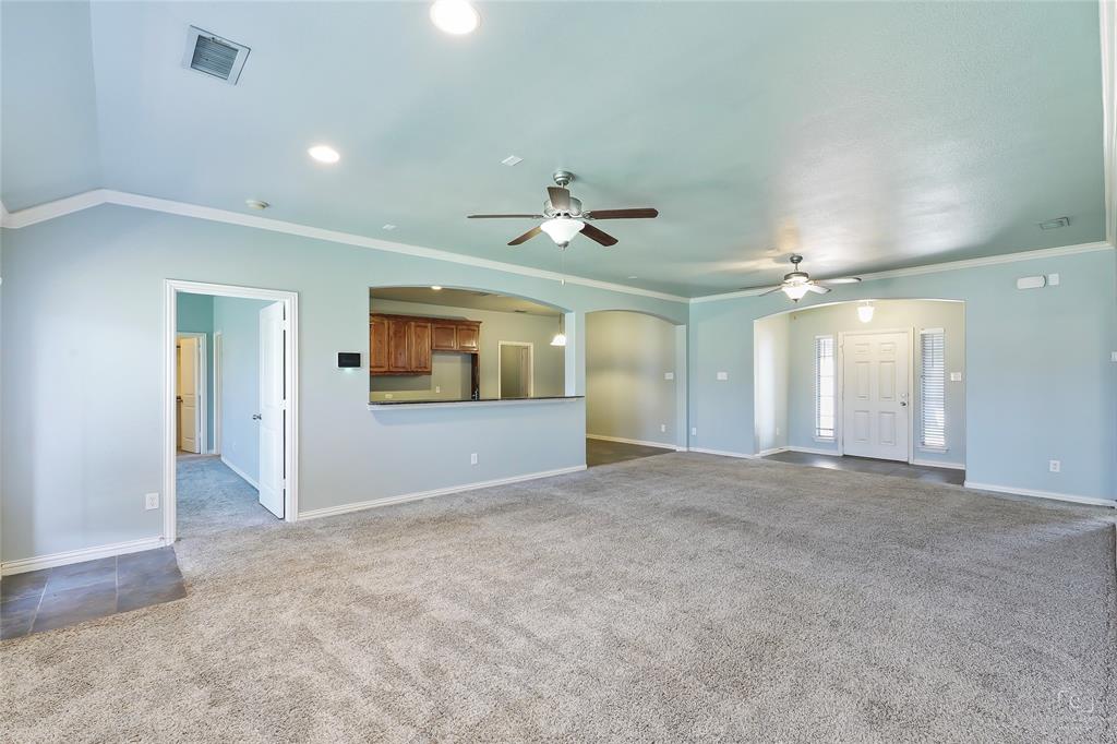 6601 Pine Hills Lane Denton, TX 76210 - Photo 8 of 23 Unfurnished living room featuring arched walkways, ornamental molding, dark carpet, and ceiling fan