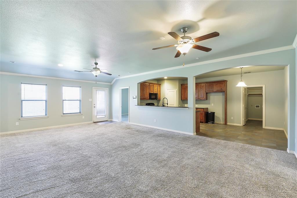 6601 Pine Hills Lane Denton, TX 76210 - Photo 9 of 23 Unfurnished living room with crown molding, arched walkways, dark colored carpet, and ceiling fan