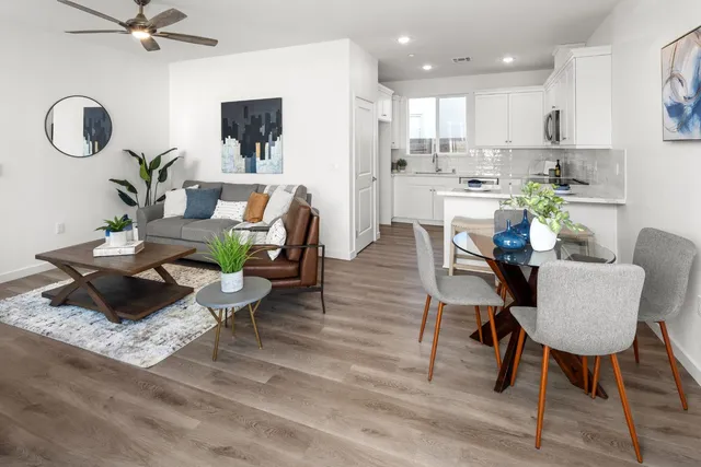 a living room with furniture kitchen view and a wooden floor