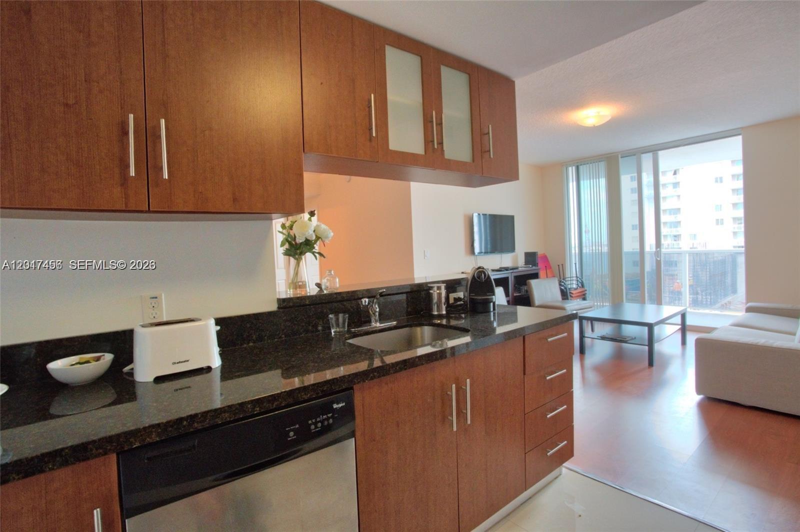 601 Northeast 23rd Street, Unit 1004 Miami, FL 33137 - Photo 5 of 17 a kitchen with granite countertop a sink a stove and cabinets