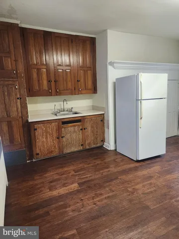 a view of large kitchen with granite countertop stainless steel appliances refrigerator sink and wooden floor