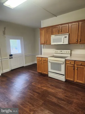 a kitchen with stainless steel appliances granite countertop a stove top oven a sink dishwasher and a refrigerator with wooden floor