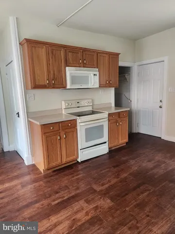 a kitchen with stainless steel appliances granite countertop a stove a sink and a refrigerator with wooden floors