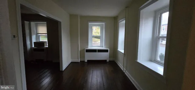 a view of a hallway with wooden floor and windows