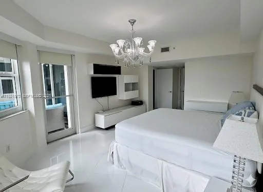 a spacious bedroom with a bed and a chandelier