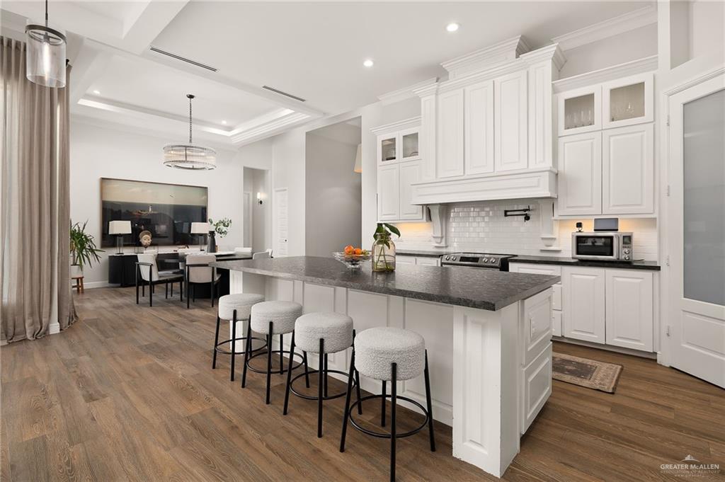 1803 Melissa Rae Drive Mission, TX 78572 - Photo 6 of 31 Kitchen with white cabinetry, a breakfast bar, decorative backsplash, a kitchen island, and dark wood-style flooring