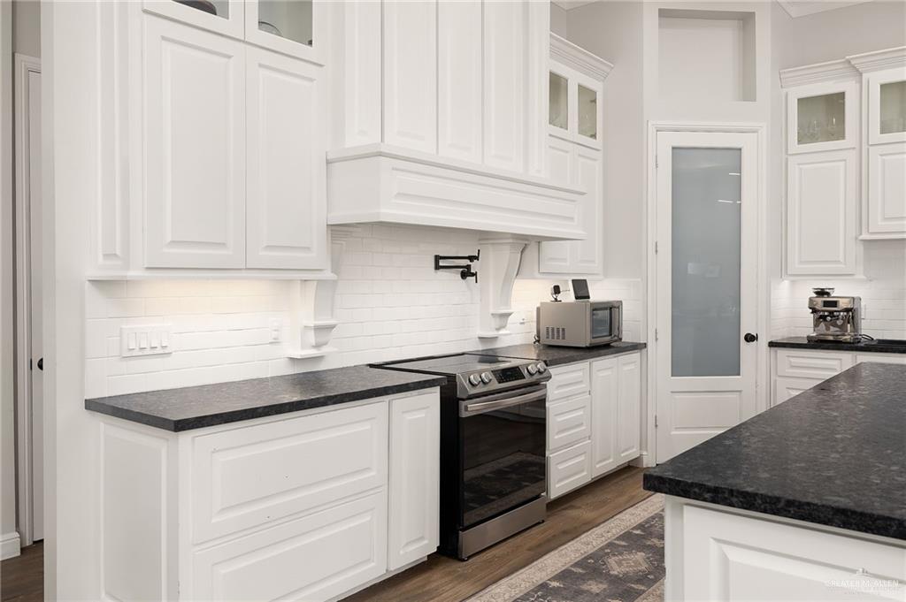 1803 Melissa Rae Drive Mission, TX 78572 - Photo 7 of 31 Kitchen featuring white cabinetry, glass insert cabinets, stainless steel appliances, and decorative backsplash