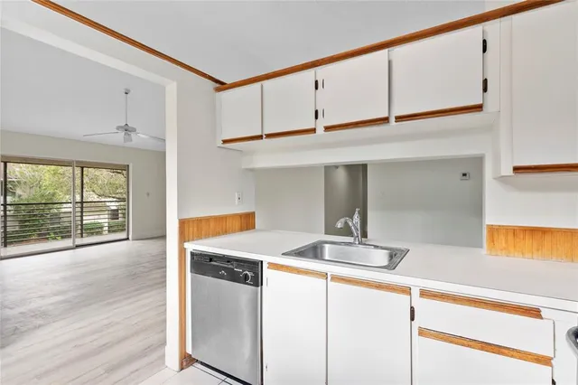 a kitchen with stainless steel appliances granite countertop a sink and white cabinets with wooden floor