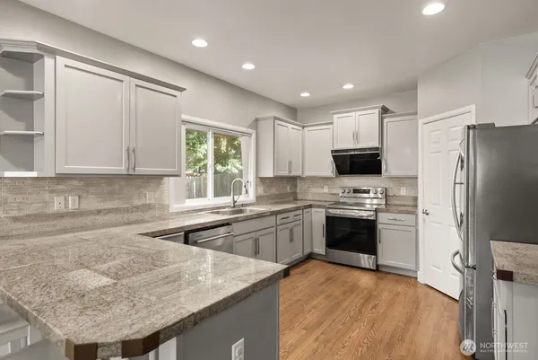 a kitchen with stainless steel appliances granite countertop a sink stove refrigerator and cabinets