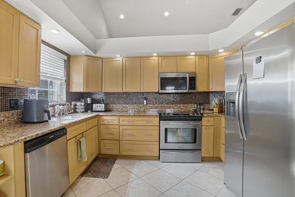 a kitchen with stainless steel appliances granite countertop a sink a stove a refrigerator and a microwave
