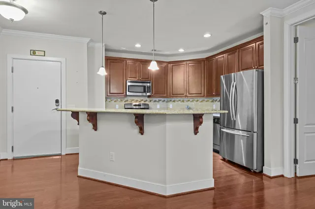 a kitchen with kitchen island a refrigerator stove and wooden floor