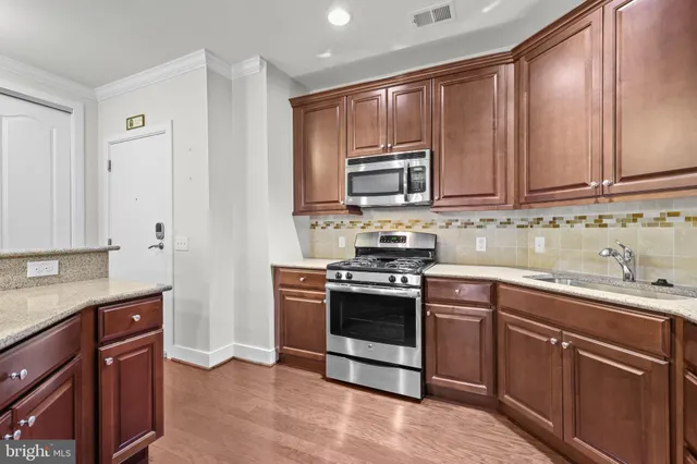 a kitchen with stainless steel appliances granite countertop a stove a sink and a microwave