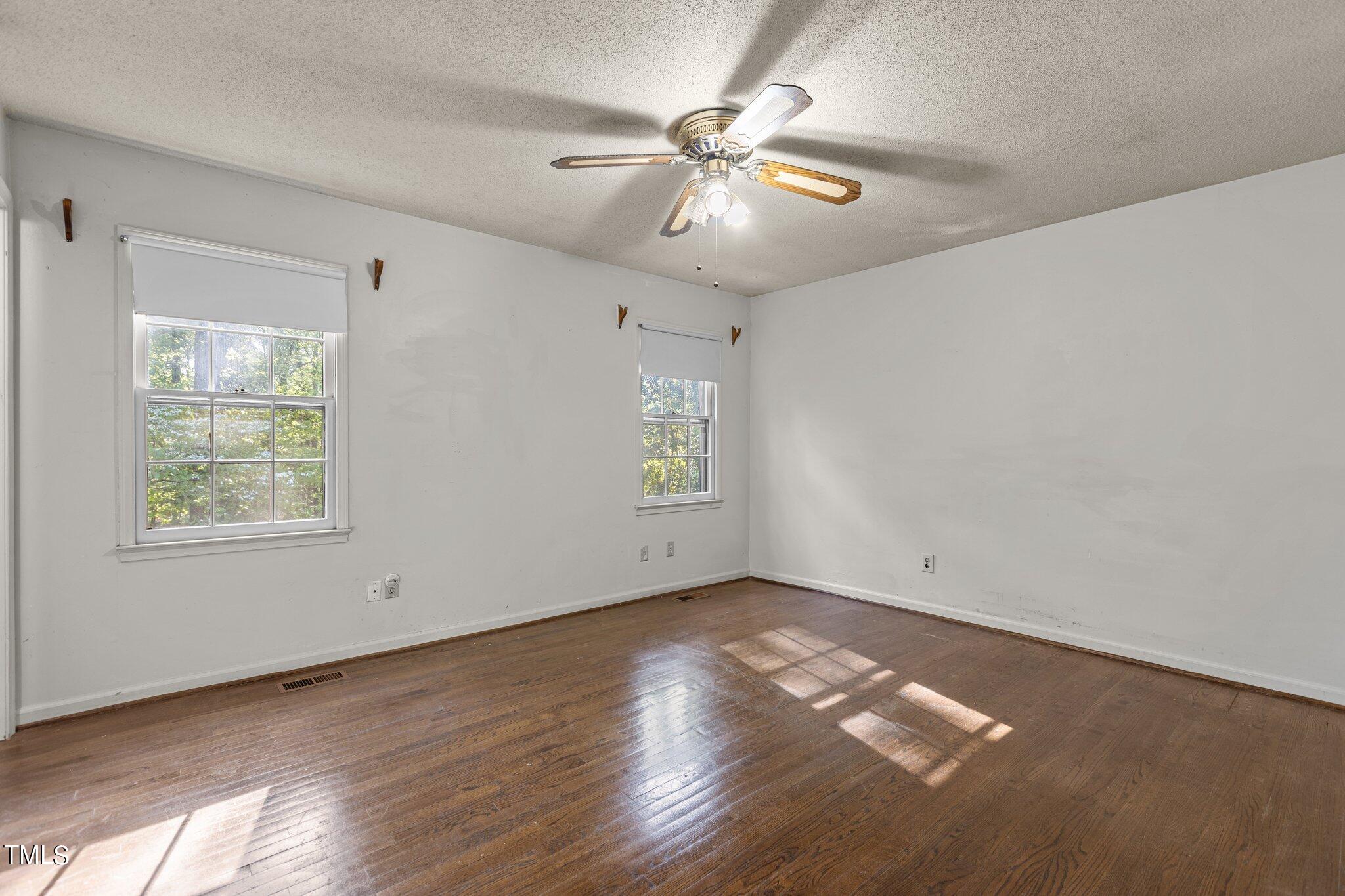 1500 Princess Anne Road Raleigh, NC 27607 - Photo 18 of 37 an empty room with wooden floor chandelier fan and windows