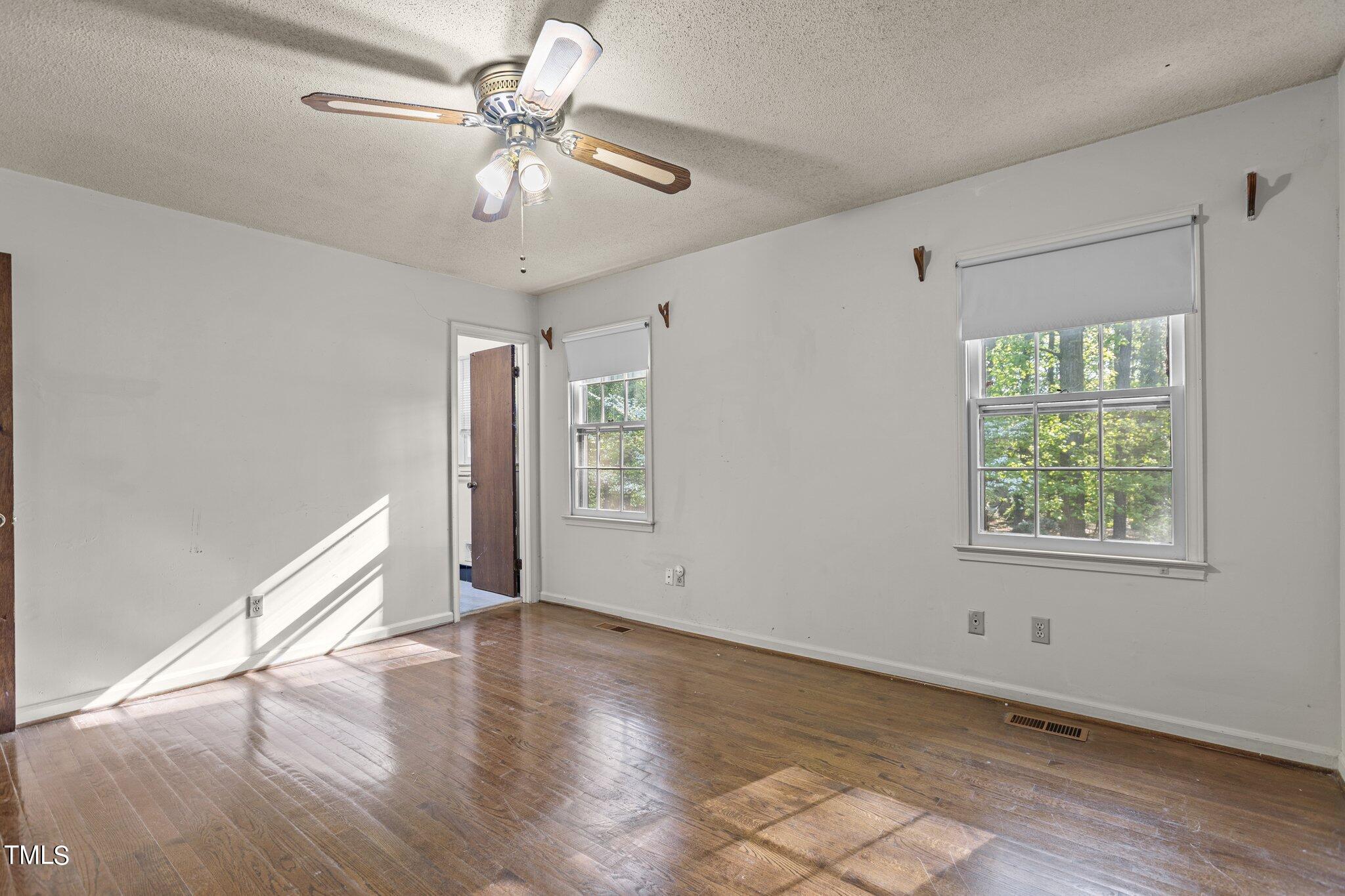 1500 Princess Anne Road Raleigh, NC 27607 - Photo 19 of 37 an empty room with wooden floor chandelier fan and windows