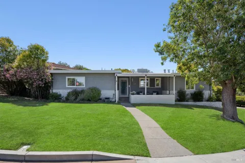a front view of a house with a garden and trees
