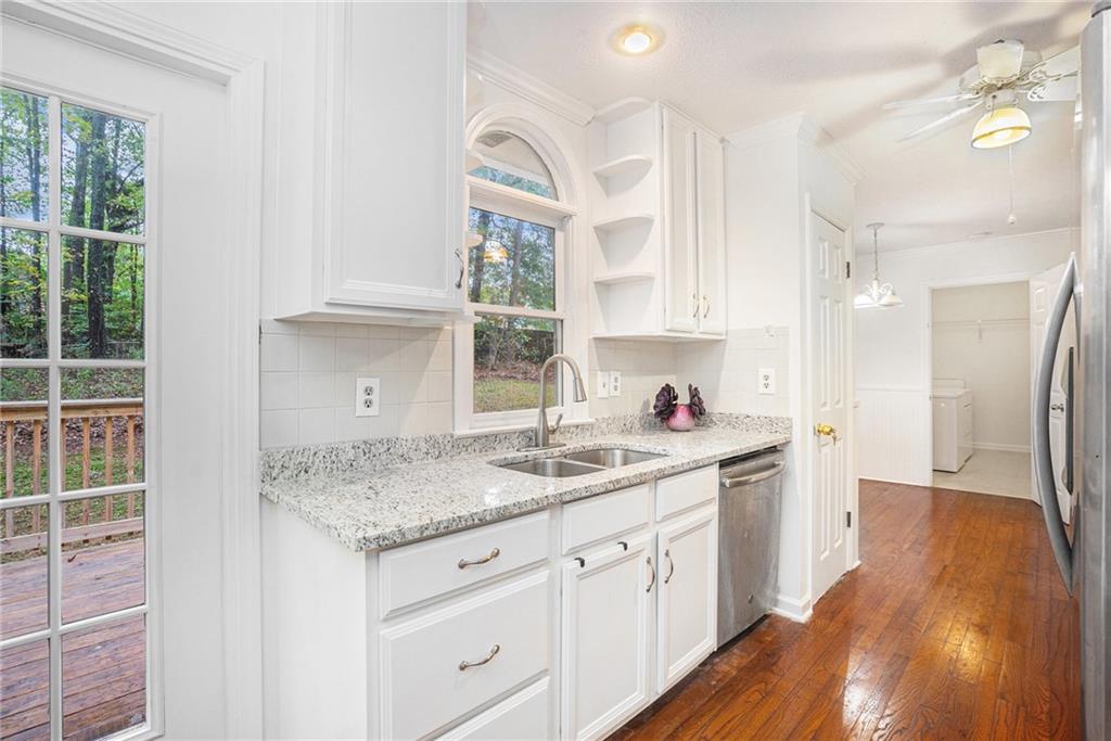 1883 Suwanee Terrace Northwest Suwanee, GA 30024 - Photo 4 of 25 a kitchen with a sink dishwasher and white cabinets with wooden floor