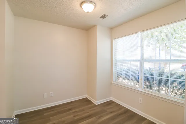 an empty room with wooden floor and windows
