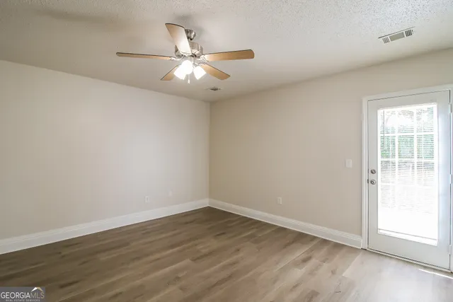 an empty room with wooden floor fan and windows