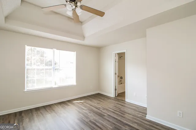 a view of an empty room with a window and wooden floor