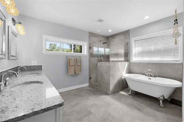 a spacious bathroom with a granite countertop sink and a bathtub