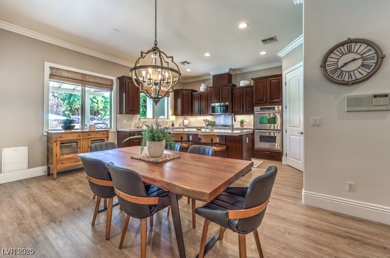 9135 Hickam Avenue Las Vegas, NV 89129 - Photo 16 of 75 Dining area featuring ornamental molding, a chandelier, light wood-style floors, and recessed lighting