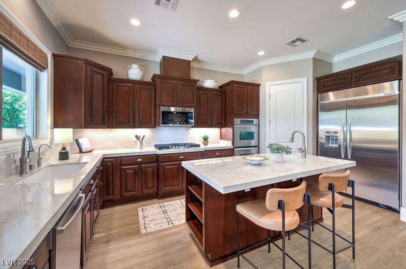 9135 Hickam Avenue Las Vegas, NV 89129 - Photo 17 of 75 Kitchen featuring appliances with stainless steel finishes, a center island with sink, light wood finished floors, open shelves, and recessed lighting