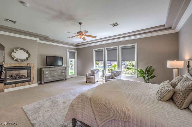 9135 Hickam Avenue Las Vegas, NV 89129 - Photo 30 of 75 Bedroom with carpet floors, crown molding, a tile fireplace, a tray ceiling, and a ceiling fan