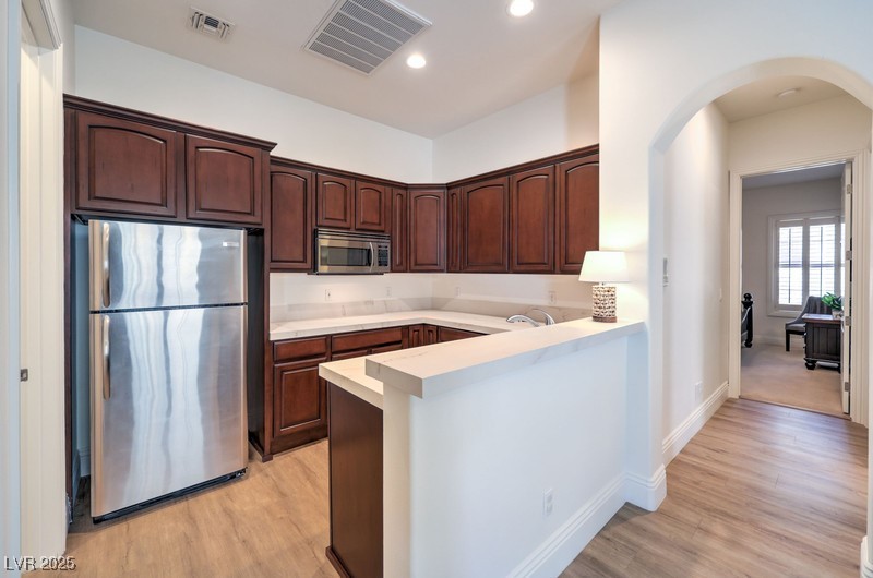 9135 Hickam Avenue Las Vegas, NV 89129 - Photo 42 of 75 Kitchen with stainless steel appliances, a peninsula, arched walkways, light countertops, and recessed lighting