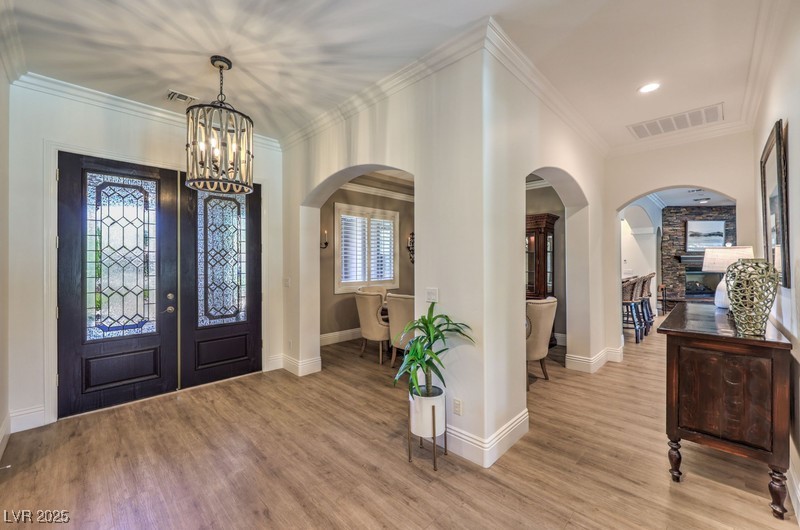 9135 Hickam Avenue Las Vegas, NV 89129 - Photo 8 of 75 Entryway featuring arched walkways, french doors, a chandelier, light wood finished floors, and ornamental molding