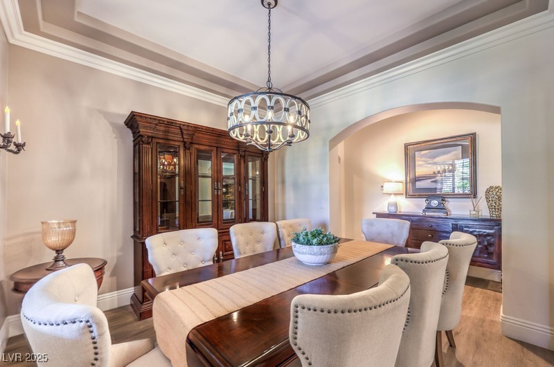 9135 Hickam Avenue Las Vegas, NV 89129 - Photo 9 of 75 Dining area featuring arched walkways, a raised ceiling, light wood-type flooring, a chandelier, and crown molding