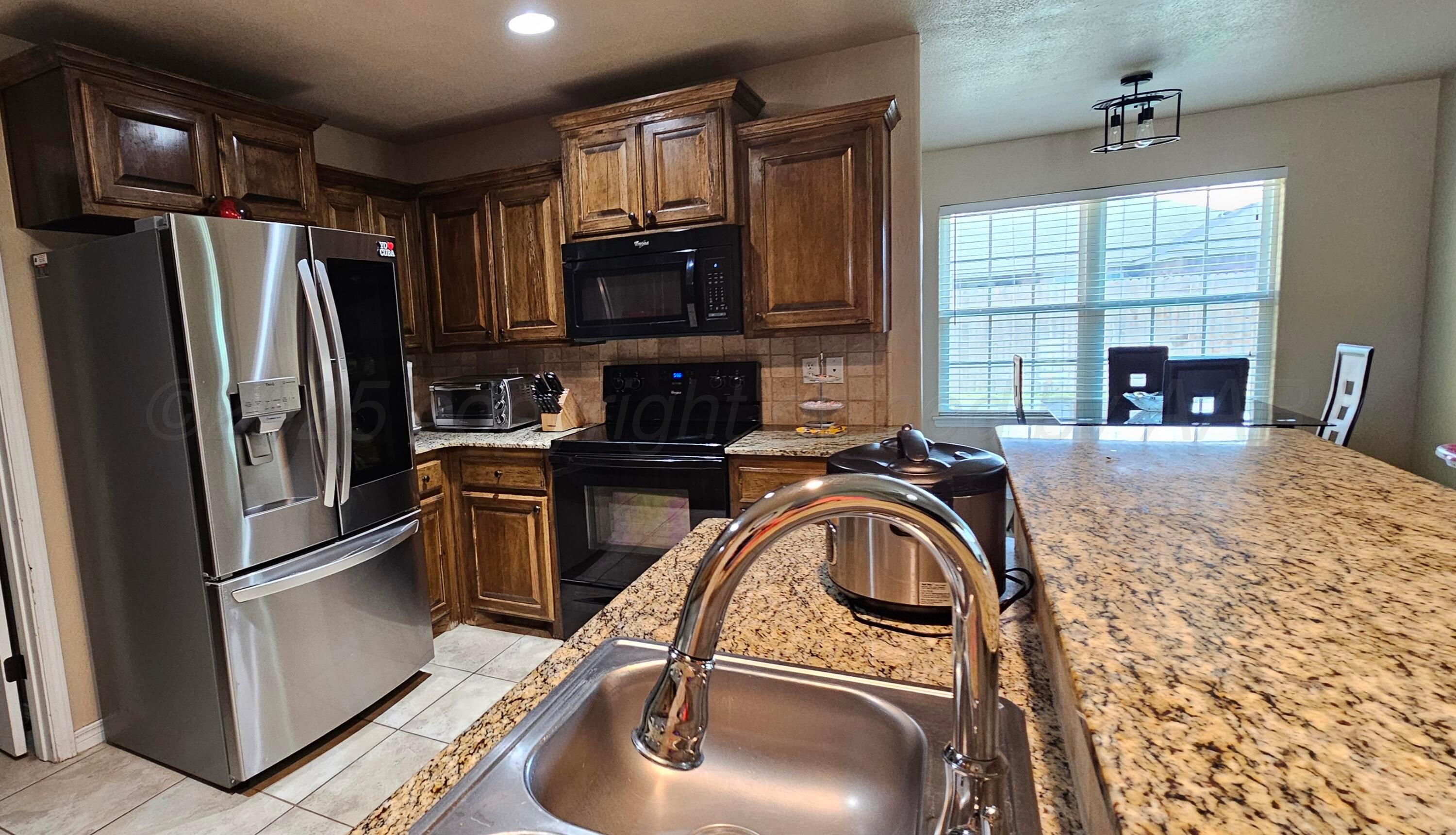 1819 Wagon Trail Road Dalhart, TX 79022 - Photo 2 of 15 a kitchen with stainless steel appliances granite countertop a sink a stove and a refrigerator