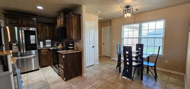 a kitchen with stainless steel appliances kitchen island granite countertop a refrigerator and a stove top oven