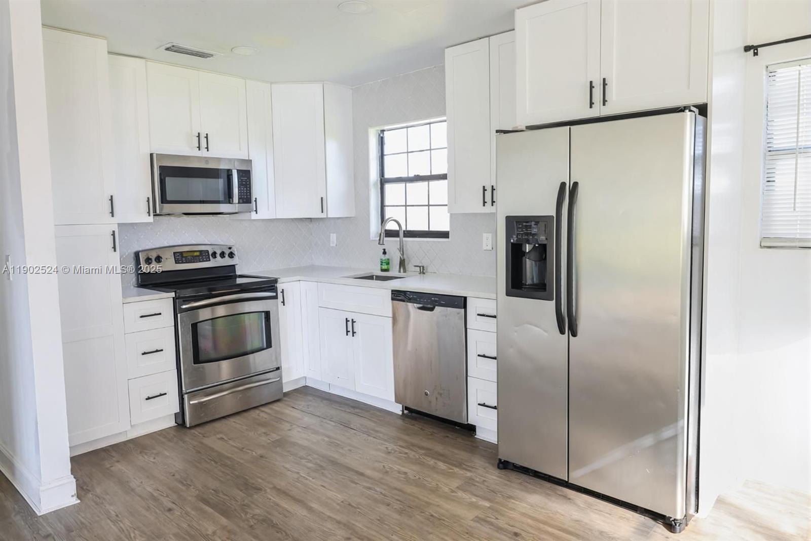 3216 22nd Street Southwest Lehigh Acres, FL 33976 - Photo 5 of 28 a kitchen with white cabinets and stainless steel appliances