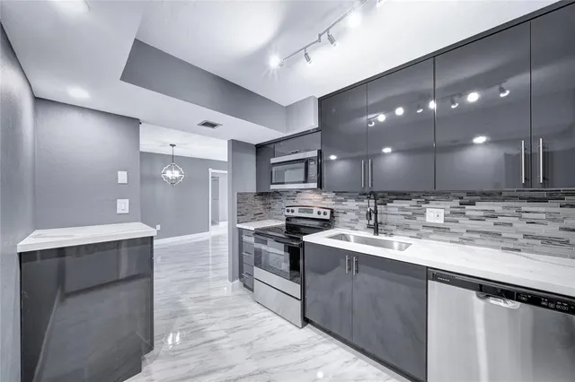 a kitchen with stainless steel appliances granite countertop a sink a stove and a wooden floors