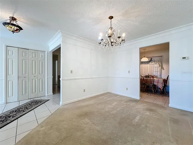 a view of a dining room and livingroom with furniture wooden floor a rug a flat screen tv and a chandelier