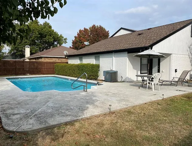 a view of a backyard with table and chairs under an umbrella