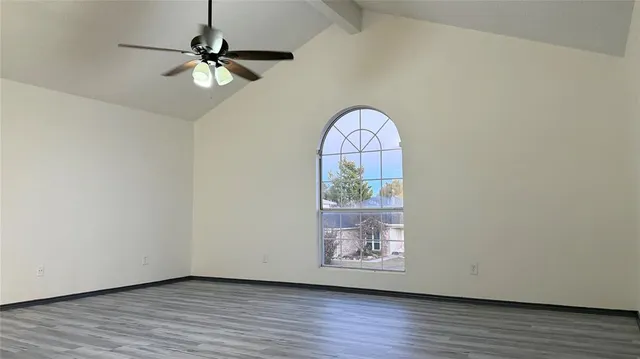 an empty room with wooden floor fan and windows