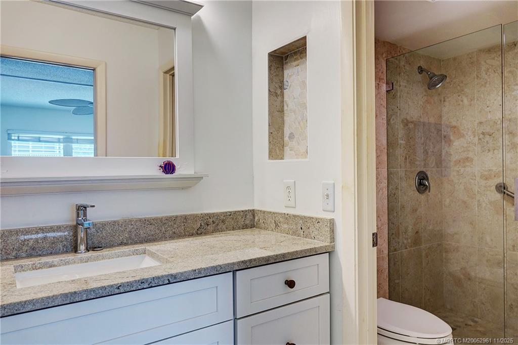 1550 Northeast Ocean Boulevard, Unit B101 Stuart, FL 34996 - Photo 18 of 32 a bathroom with a granite countertop sink a toilet and shower