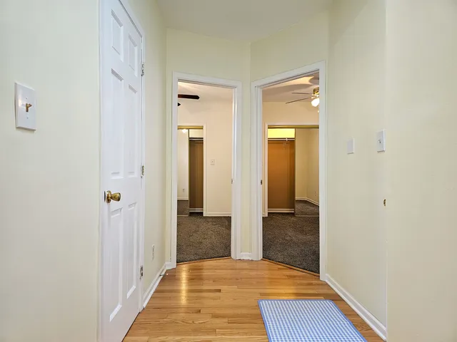 a view of a hallway with wooden floor and a bathroom