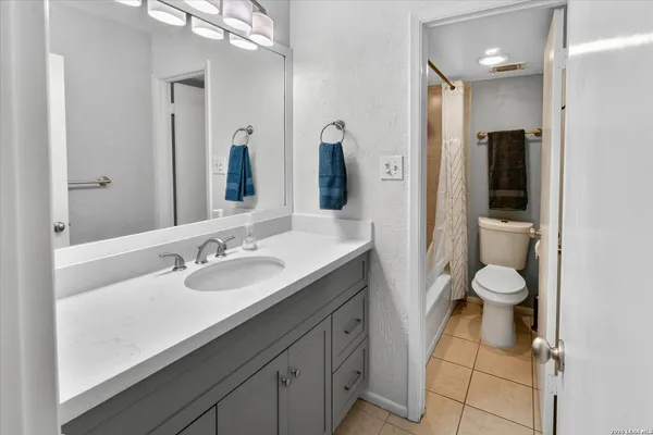 a bathroom with a granite countertop toilet sink and mirror