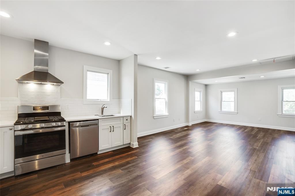 a kitchen with stainless steel appliances a stove and wooden floor