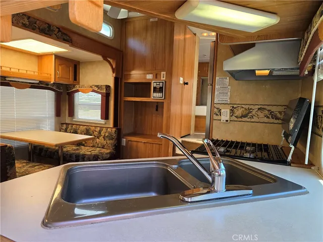 a kitchen with stainless steel appliances granite countertop a refrigerator a stove a sink dishwasher and wooden cabinets with wooden floor