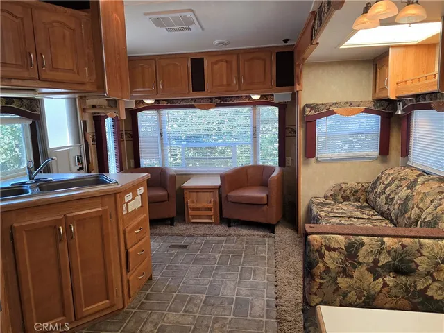 a kitchen with stainless steel appliances granite countertop a refrigerator a stove and a sink with wooden cabinets