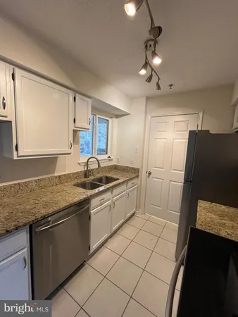a large kitchen with granite countertop a sink stainless steel appliances and cabinets