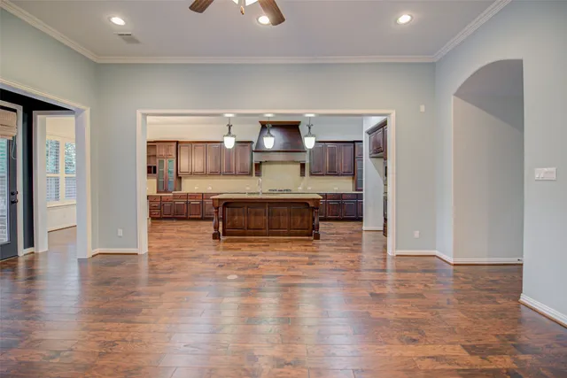 a living room with stainless steel appliances kitchen island granite countertop a stove and a wooden floors