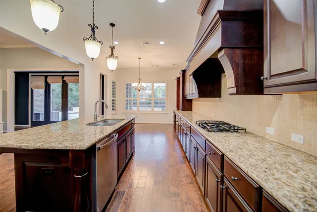 a kitchen with kitchen island granite countertop a sink a counter space appliances and cabinets